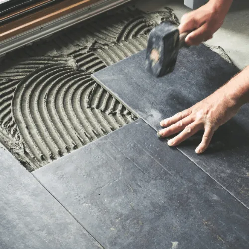 Professional installer setting a dark floor tile